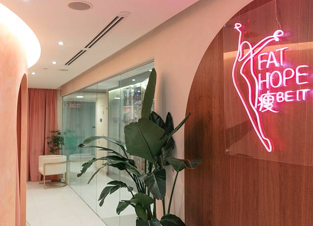 fat-reduction-treatment-hallway Interior hallway with plants and neon wall sign inside a fat reduction treatment space